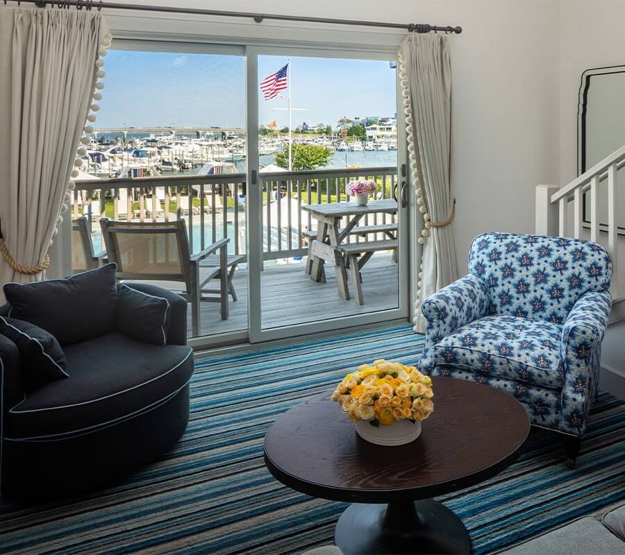 living room chairs and furniture with sliding glass door to deck overlooking the harbor