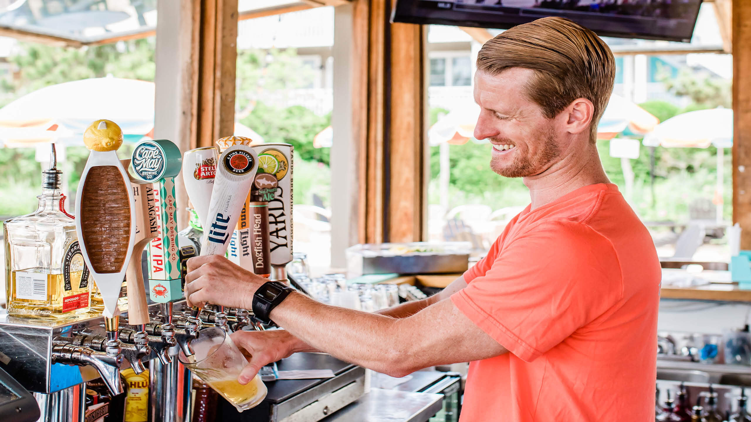 A happy bartender pouring a glass of beer from the draft 