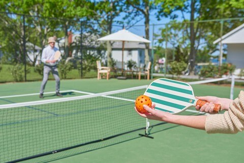 woman serving a pickle ball on a court